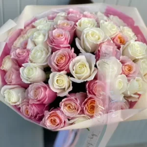 A woman gracefully holds a large bouquet of vibrant roses, showcasing their beauty and elegance in her hands.