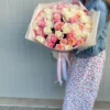 A woman gracefully holds a large bouquet of vibrant roses, showcasing their beauty and elegance in her hands.